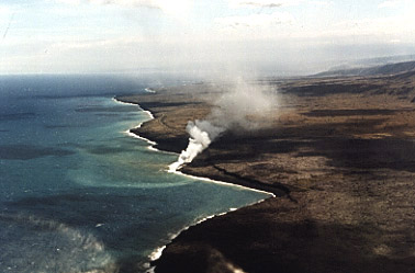 Photo of steam rising from a lava flow entering the ocean.